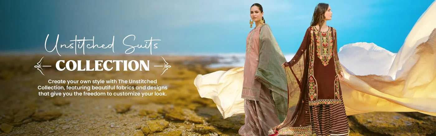 Two women in traditional suits stand on a rocky beach, flowing fabric around them, promoting the unstitched suits collection with customizable options for a unique look.